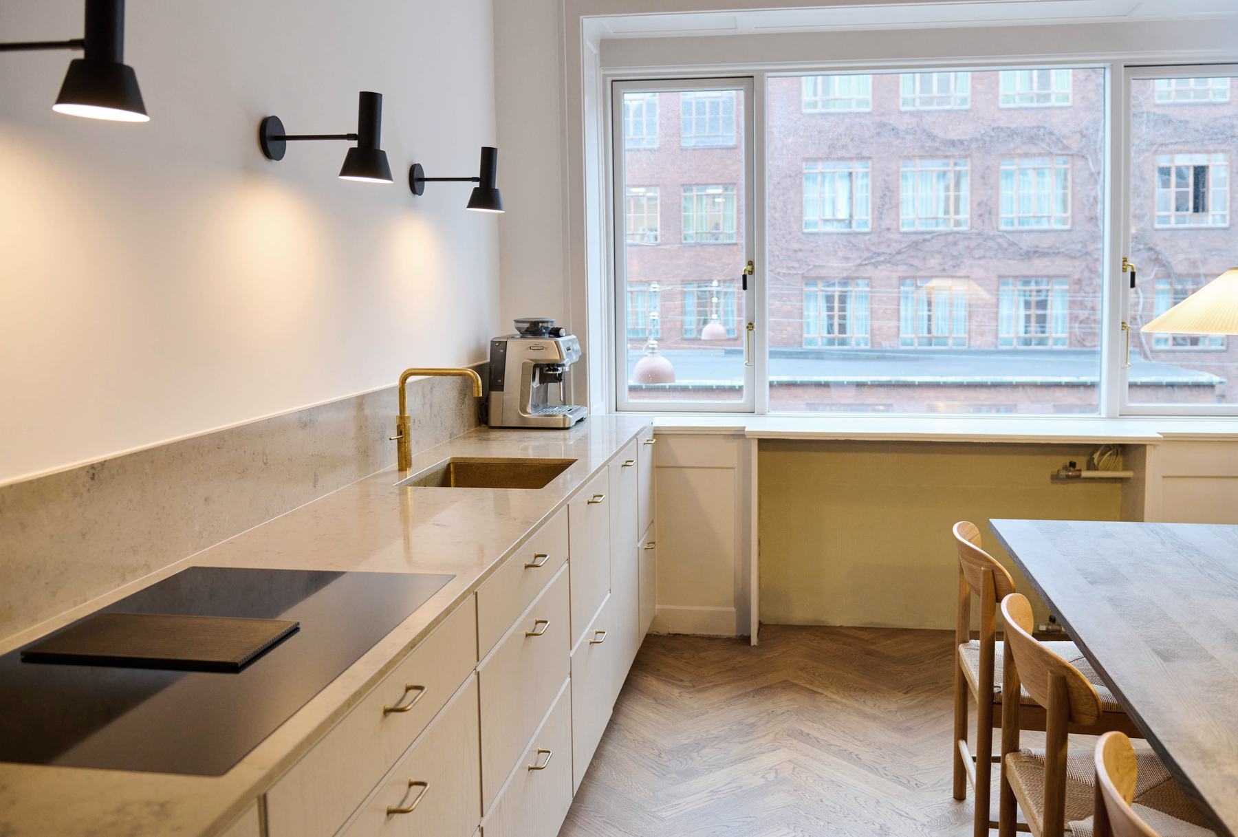 Køkken med sandfarvede fronter, stenbordplade og messinggreb