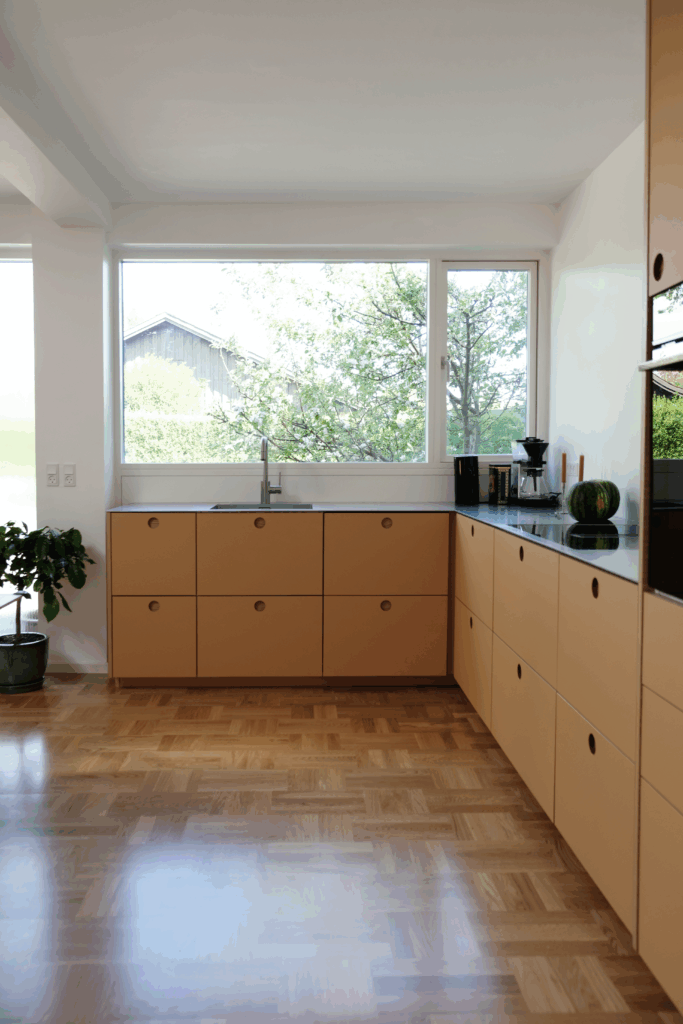 Moderne beige køkken med store vinduer og mørk bordplade som inspiration til dig der vil vide hvad koster et køkken.