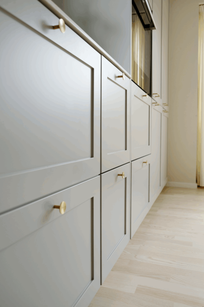 Nye grå køkkenlåger med messinggreb, som viser detaljeniveau og materialevalg, der påvirker, hvad koster renovering af køkken.