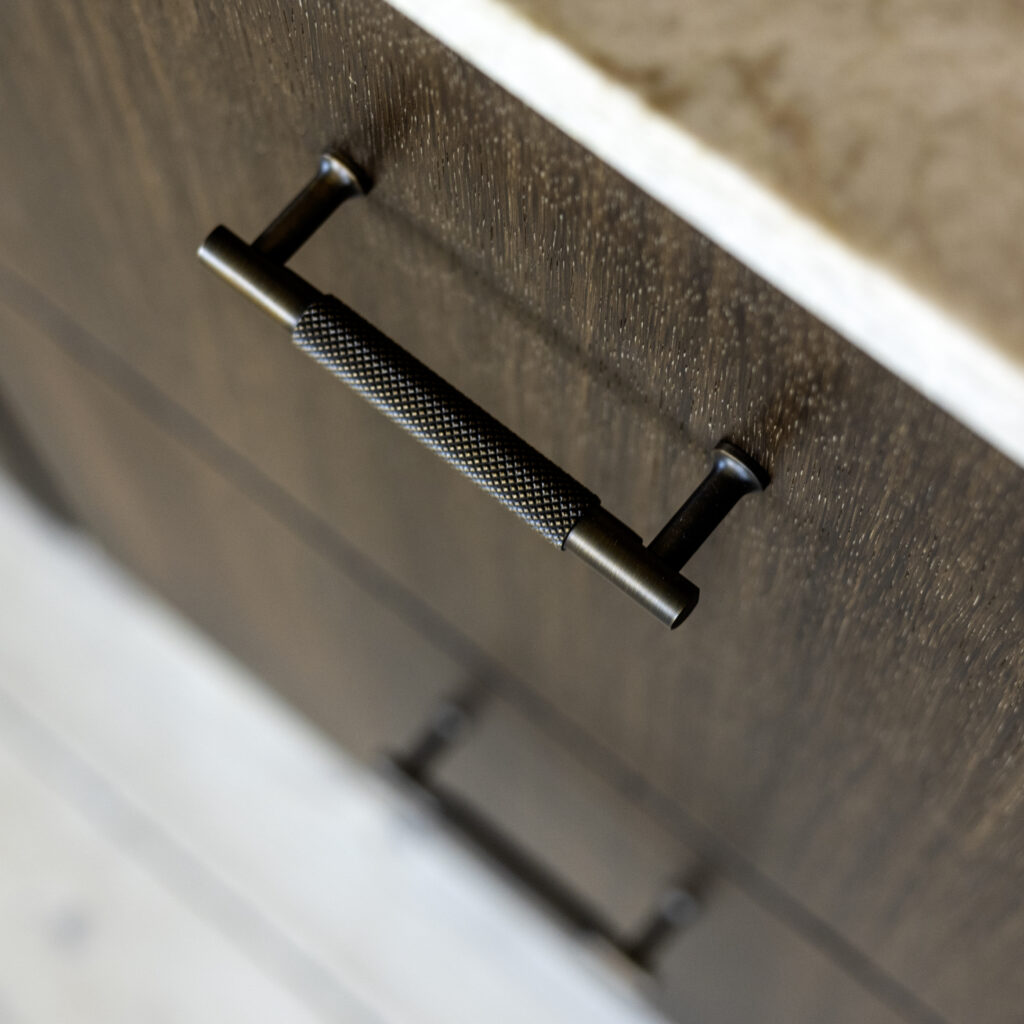Mørkt køkkendesign med sorte metalgreb og træstruktur, der viser en elegant måde at skift greb på køkkenlåger og opgradere udtrykket.