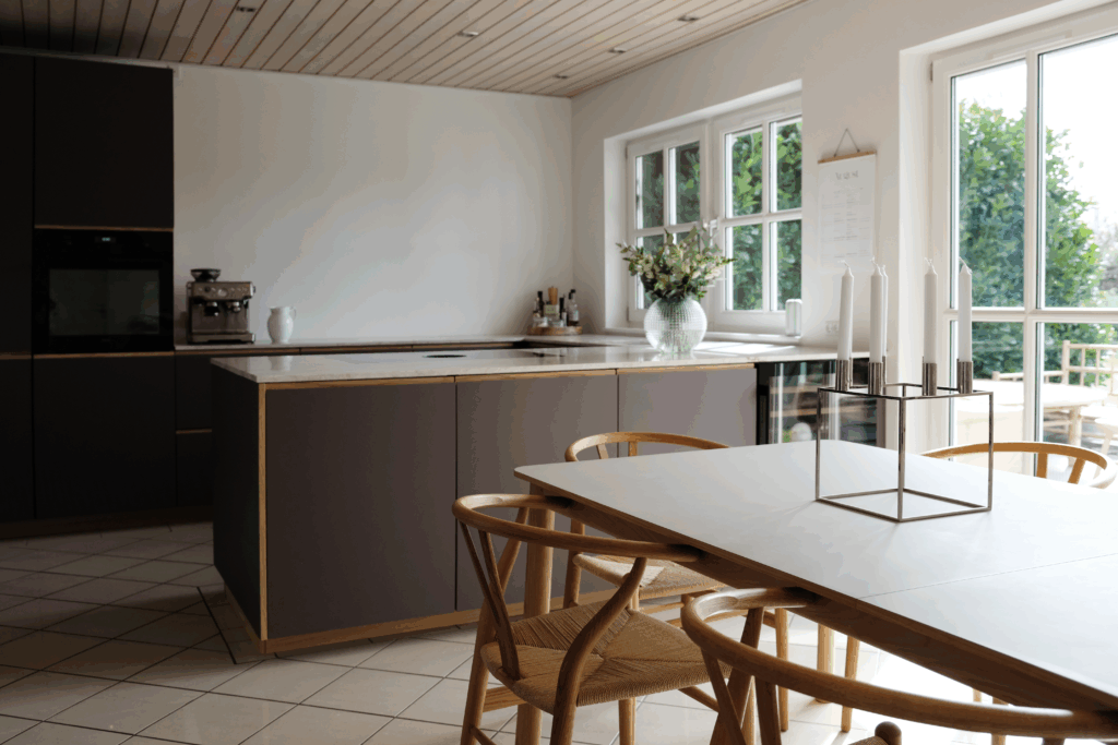 Elegant køkken med brune fronter, lys bordplade og spiseplads – et eksempel på moderne stil og prisniveau, når man overvejer, hvad koster renovering af køkken.