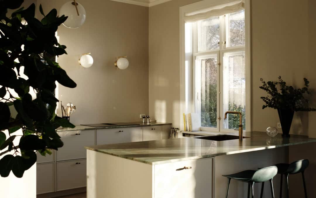 Hvidt køkken med grøn marmorbordplade, køkkenø og messingdetaljer – hvidt køkken inspiration med naturligt lys og nordisk stil.