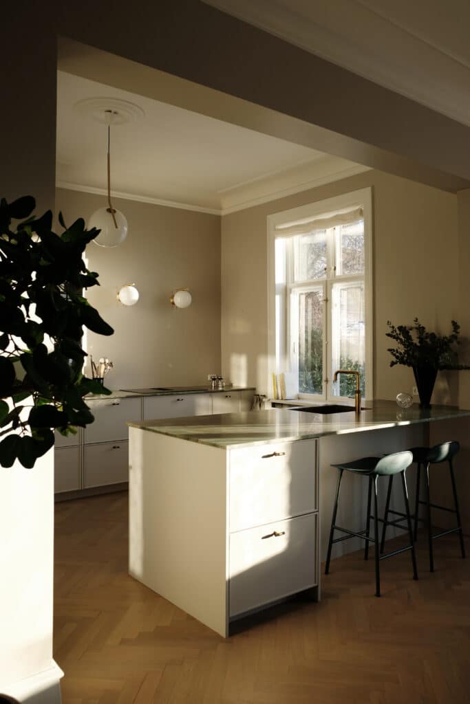 Hvidt køkken med grøn marmorbordplade, køkkenø og messingdetaljer – hvidt køkken inspiration med naturligt lys og nordisk stil.