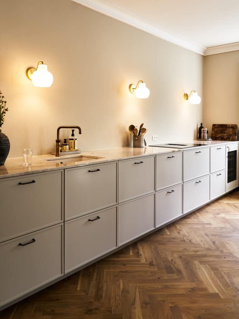 Lyst hvidt køkken med marmor bordplade, messingarmatur og klassiske væglamper – elegant hvidt køkken inspiration til moderne hjem.