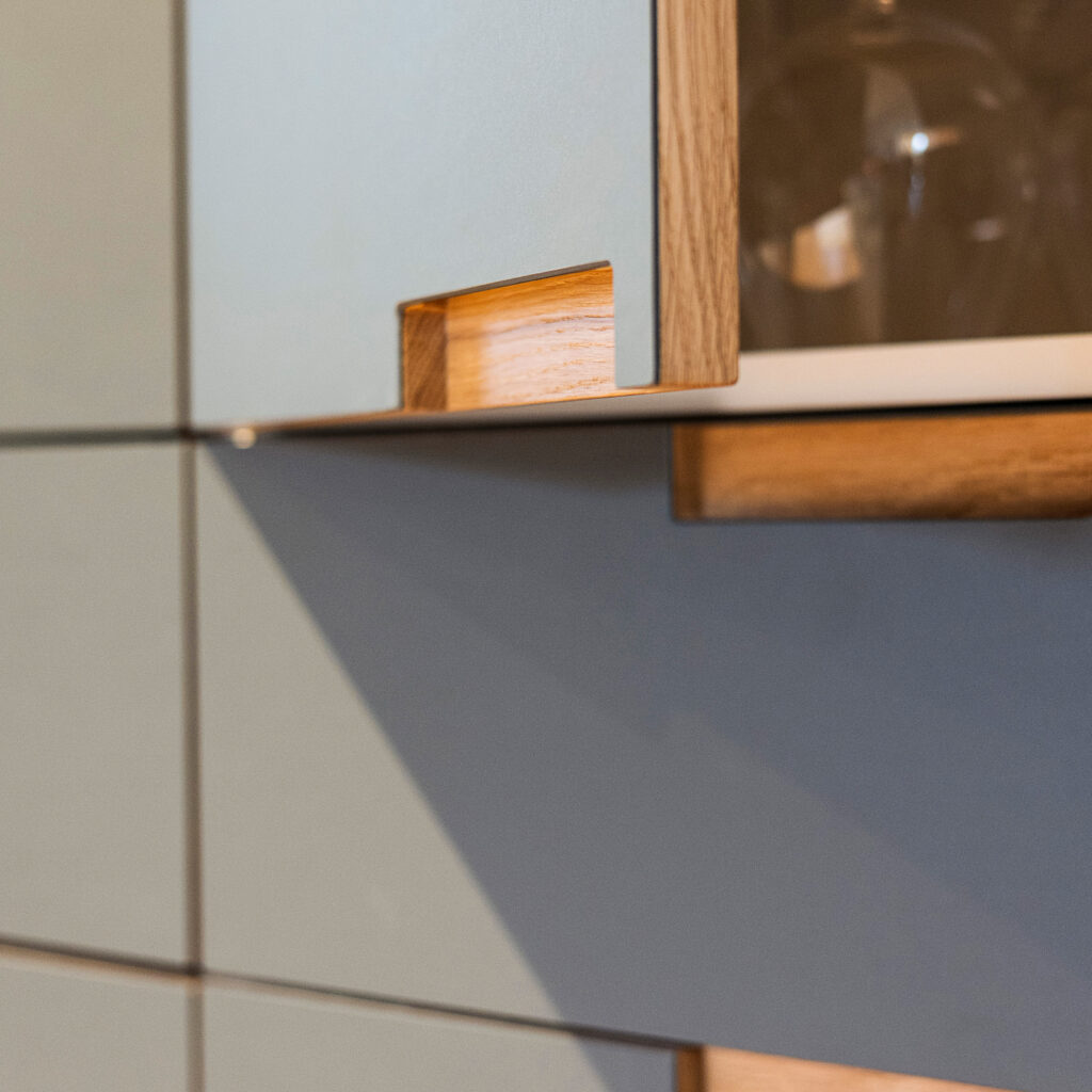 Detalje af køkkenlåge i træ og laminat med elegant udskåret greb – eksempel på materialer der viser, hvilke køkkenlåger holder bedst.