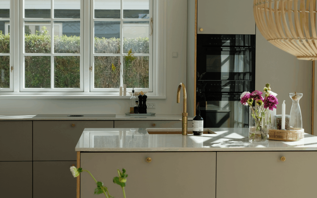 Lyst og moderne køkken med grå fronter, messingarmatur og blomster på bordet – eksempel på processen og resultatet, når man overvejer, hvor lang tid tager det at lave et nyt køkken.