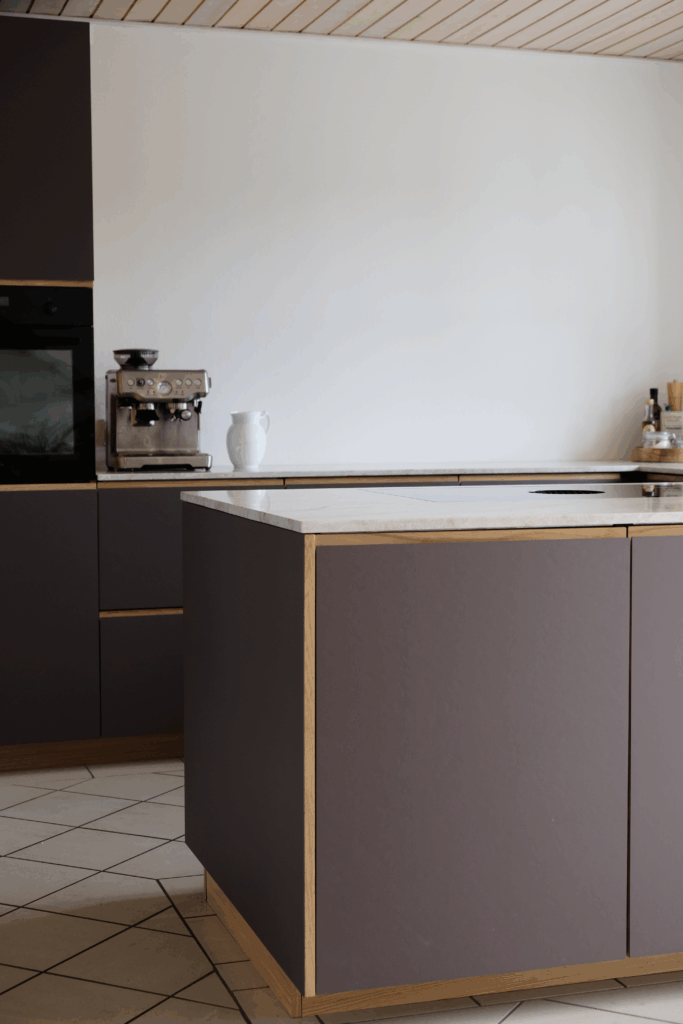 Moderne køkken med mørkebrune fronter, trækanter og køkkenø – viser resultatet af professionel montering, når man spørger, hvor lang tid tager det at sætte et køkken op.