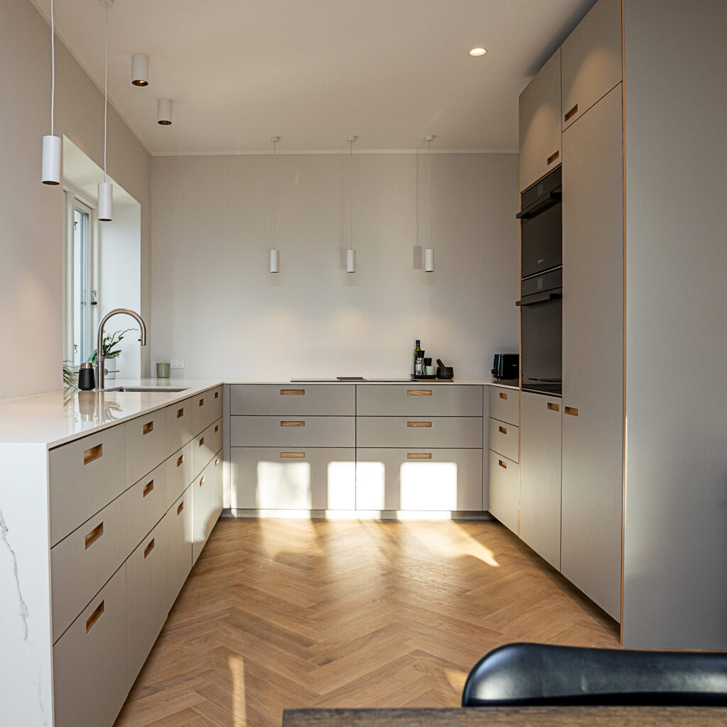 Moderne gråt køkken med indbyggede skabe og trægulv – viser resultatet af korrekt opmåling af køkken før montering.