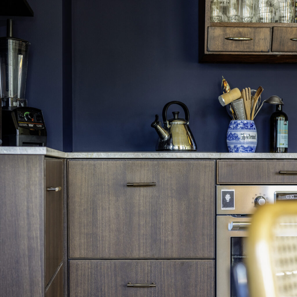 Mørkt trækkøkken med blå væg og moderne greb – inspiration til renovering af IKEA køkken med karakter og personligt udtryk.