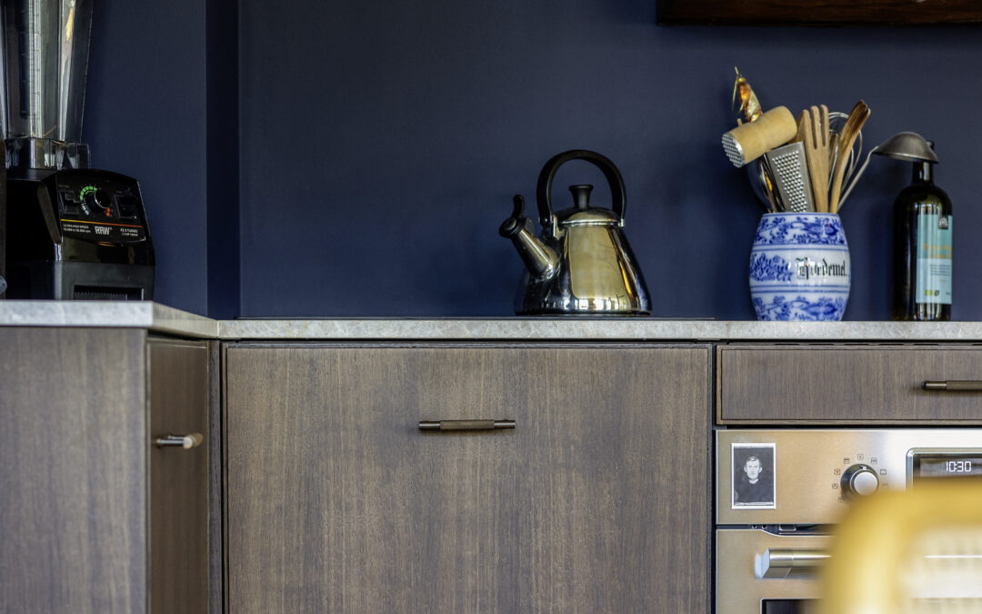 Mørkt trækkøkken med blå væg og moderne greb – inspiration til renovering af IKEA køkken med karakter og personligt udtryk.