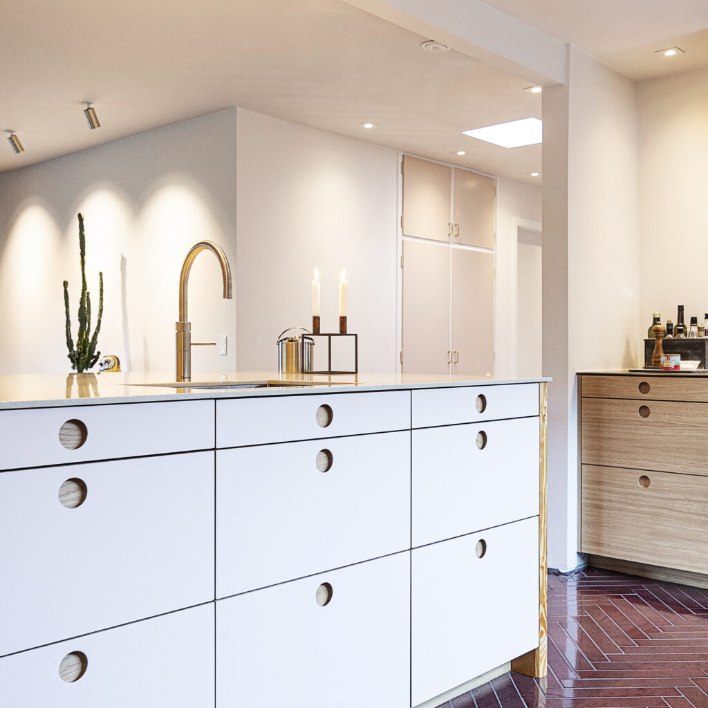 Hvidt køkken med runde greb og messingarmatur – eksempel på stilren renovering af IKEA køkken med nye fronter og detaljer.