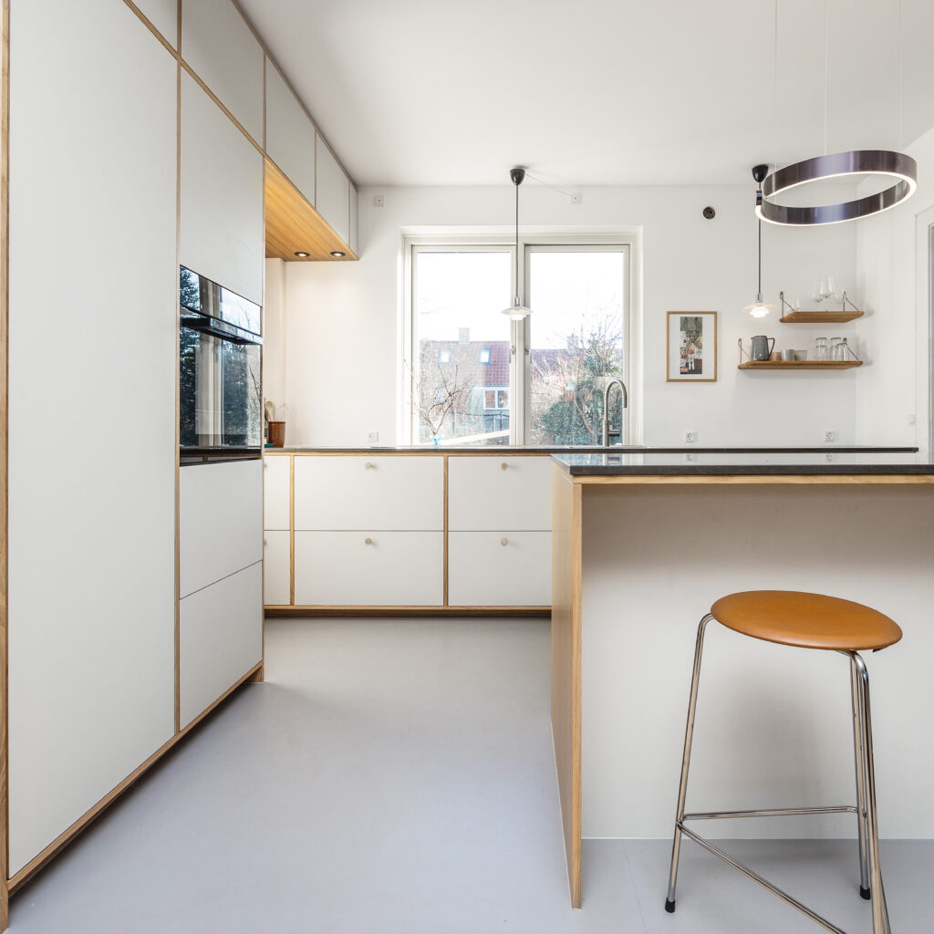 Lyst hvidt køkken med trædetaljer og stort vindue – eksempel på præcision og planlægning under opmåling af køkken.