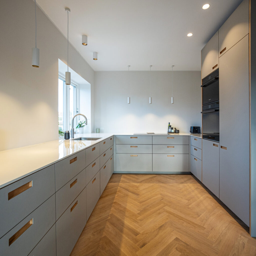 Renoveret køkken fra 70'erne med lyse materialer, nye skabsløsninger og varme trædetaljer, der giver et opdateret og tidløst udtryk.
