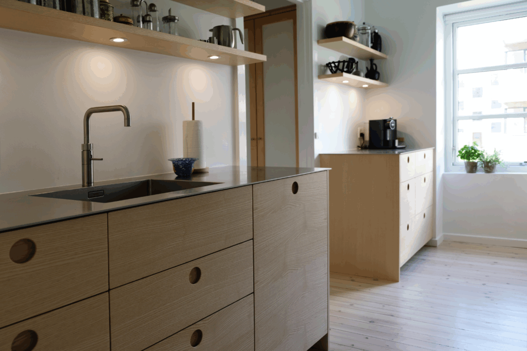 Stilfuldt køkken inspireret af 70'ernes design med naturlige træoverflader og minimalistiske linjer, der fremhæver dansk håndværk.