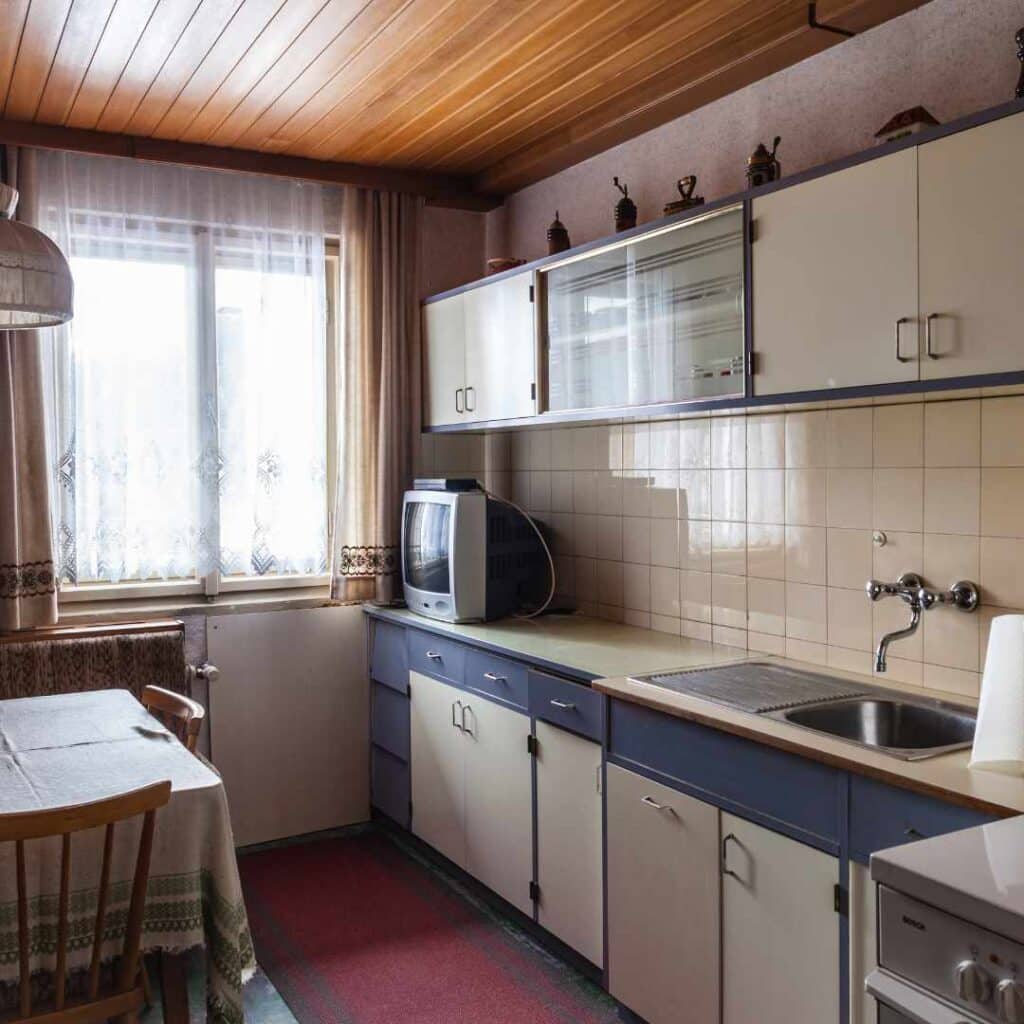 Ældre køkken med slidte skabe før renovering – inspiration til at forny gammelt køkken.