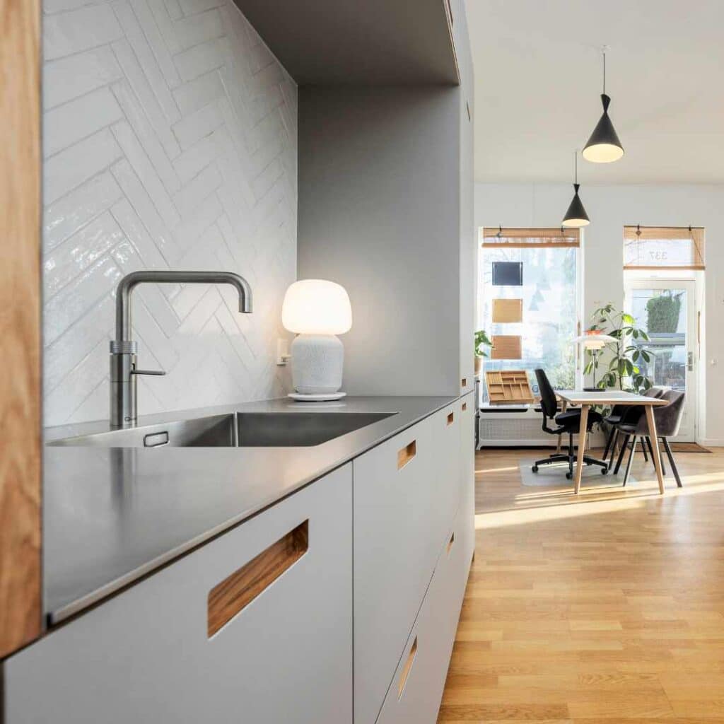 Lysegråt køkken med stilrene fronter, stålbordplade og moderne design i en lys og indbydende indretning.