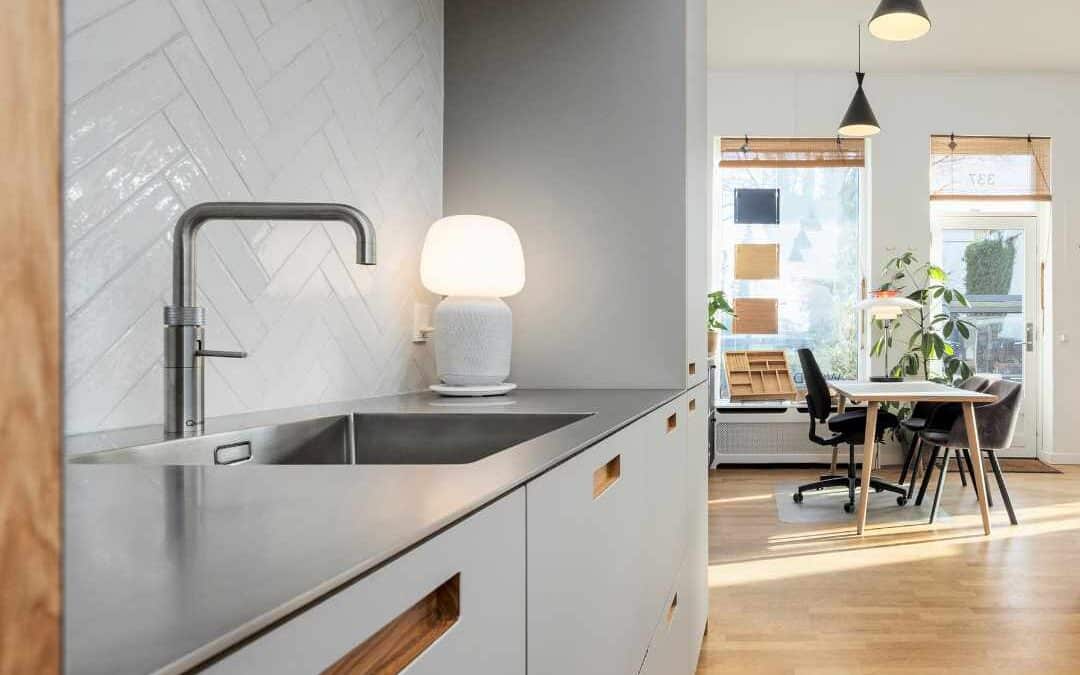 Lysegråt køkken med stilrene fronter, stålbordplade og moderne design i en lys og indbydende indretning.