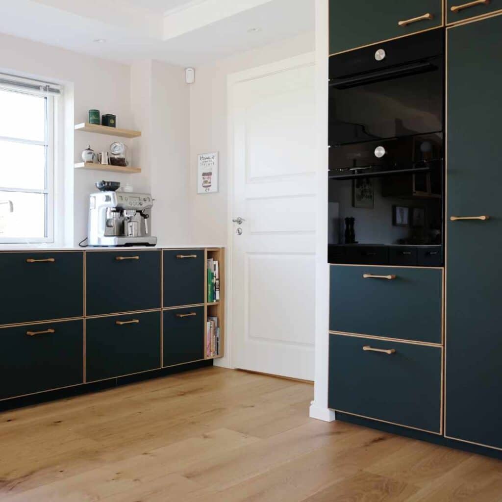 Mørkeblåt køkken med elegante fronter, trædetaljer og moderne hvidevarer i et stilfuldt design.