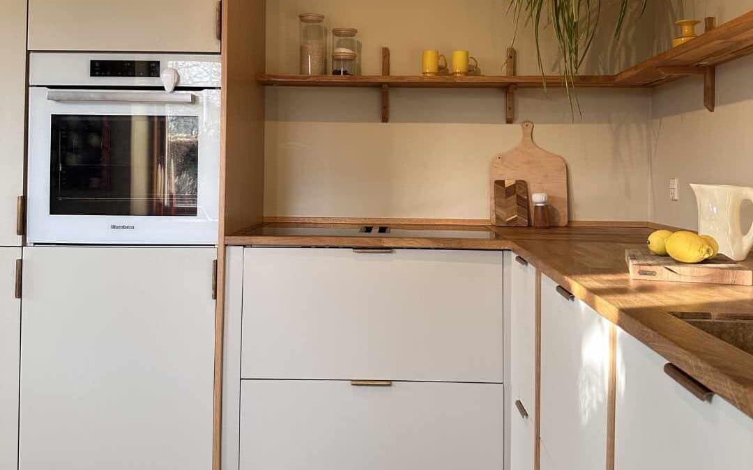 Klassisk lyst køkken med lyse fronter, træbordplade og åbne hylder i et tidløst og funktionelt design.