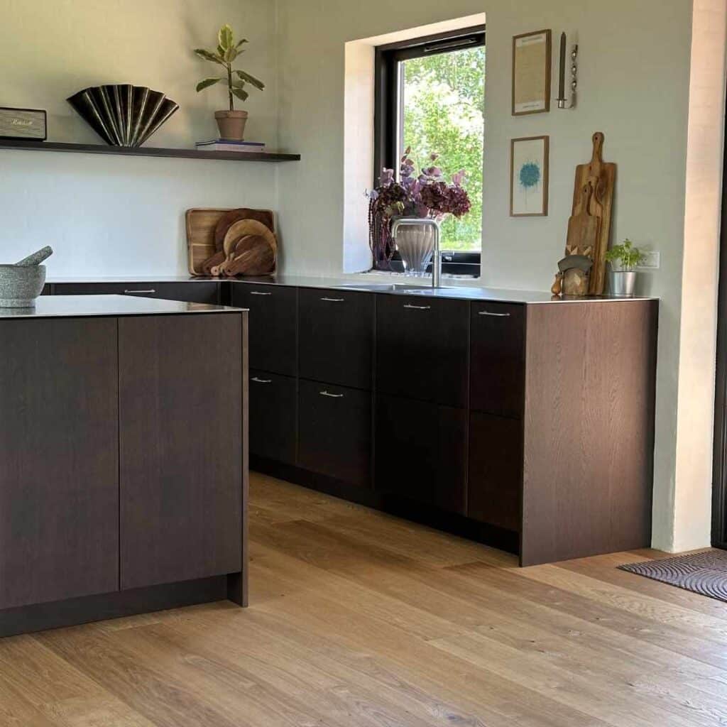 Mørkebrunt køkken med træfronter, køkkenø og naturlige materialer i eksklusivt design.