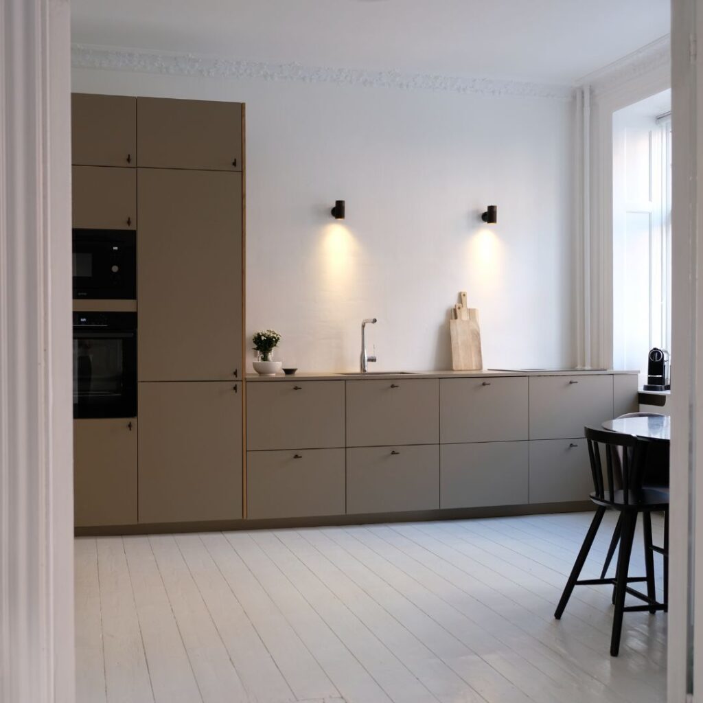 Moderne køkken med brune fronter og høje skabe.